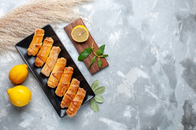 Vue de dessus de délicieux bracelets sucrés avec du citron sur une table lumineuse, gâteau pâtisserie cuire du sucre sucré