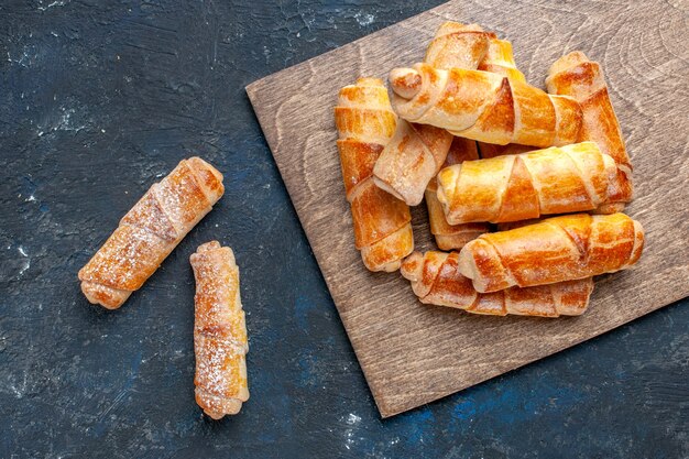 Vue de dessus de délicieux bracelets sucrés avec remplissage délicieux cuit au four sur sombre, cuire au four gâteau biscuit sucre dessert sucré