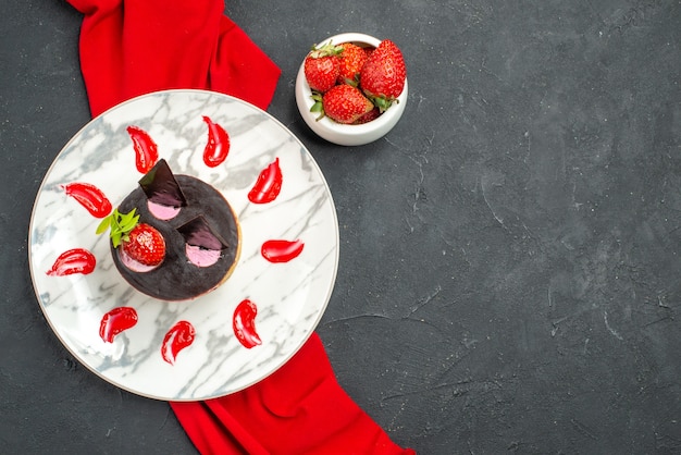 Vue de dessus délicieux cheesecake aux fraises et au chocolat sur une assiette bol châle rouge avec des fraises sur fond sombre isolé