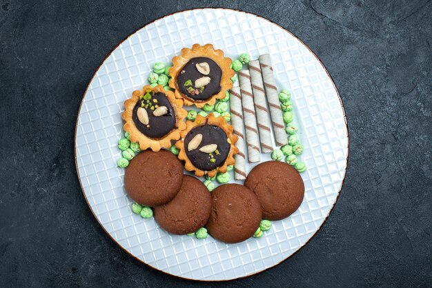 Vue de dessus de délicieux cookies avec des bonbons sur la surface gris foncé biscuit sucre cuire au four gâteau tarte thé cookie