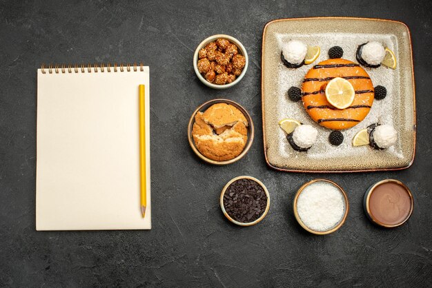 Vue de dessus délicieux dessert au gâteau avec des bonbons à la noix de coco sur une surface sombre tarte au gâteau dessert au thé aux bonbons sucrés