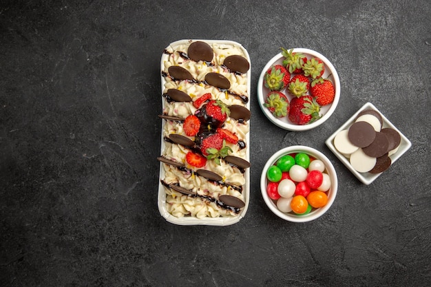 Vue de dessus délicieux dessert avec des biscuits au chocolat bonbons et fraises sur fond sombre biscuit aux noix biscuits aux fruits sucrés sucre