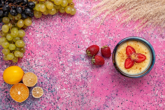 Vue de dessus délicieux dessert crémeux avec des raisins verts frais sur le dessert de bureau rose clair crème glacée aux baies de fruits sucrés