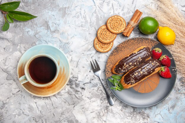 Vue de dessus de délicieux éclairs au chocolat avec des biscuits sur un biscuit de dessert au gâteau de table blanc