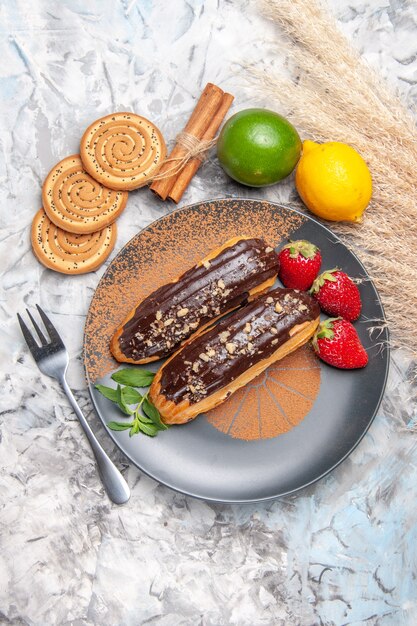 Vue de dessus de délicieux éclairs au chocolat avec des biscuits sur un biscuit de gâteau de dessert de table légère