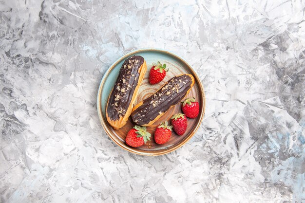 Vue de dessus de délicieux éclairs au chocolat avec des fraises sur des fruits de gâteau de dessert léger