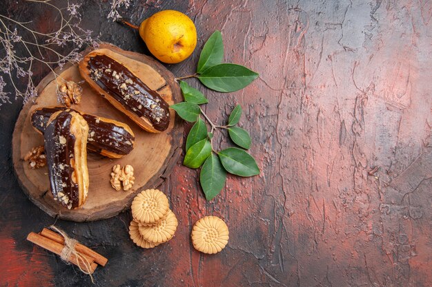 Vue de dessus de délicieux éclairs de choco avec des biscuits sur le dessert sucré de gâteau de table sombre