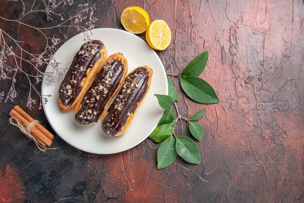 Vue de dessus de délicieux éclairs de choco à l'intérieur de la plaque sur la tarte au gâteau sucré dessert table sombre