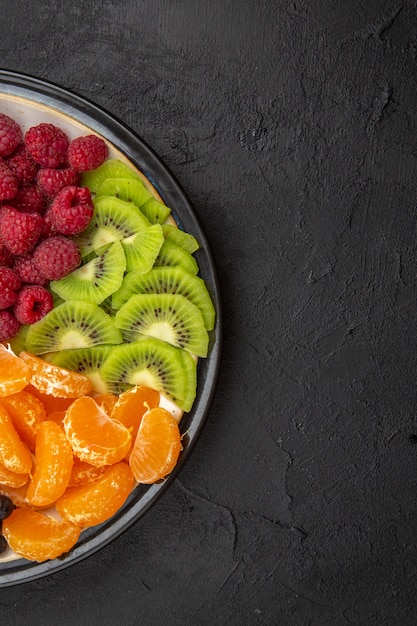 Photo gratuite vue de dessus de délicieux fruits tranchés à l'intérieur de la plaque sur l'arbre fruitier noir photo de régime mûr exotique tropical