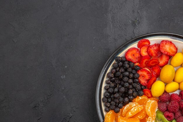 Vue de dessus de délicieux fruits tranchés à l'intérieur de la plaque sur un arbre fruitier tropical sombre régime alimentaire mûr exotique photo place libre