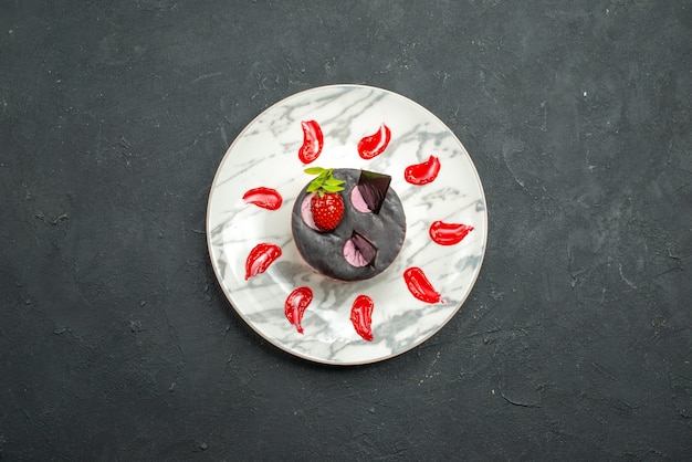 Vue de dessus un délicieux gâteau aux fraises et au chocolat sur une assiette ovale sur fond sombre