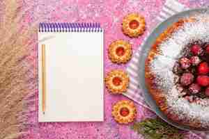 Photo gratuite vue de dessus délicieux gâteau aux fraises avec bloc-notes et sur une surface rose clair