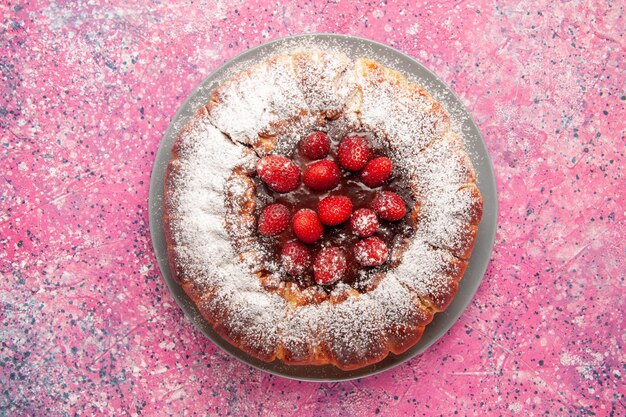 Vue de dessus délicieux gâteau aux fraises avec du sucre en poudre sur la surface rose clair