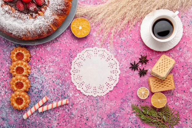 Vue de dessus délicieux gâteau aux fraises gâteau en poudre de sucre avec des biscuits gaufres et tasse de thé sur le gâteau de bureau rose tarte aux biscuits au sucre sucré