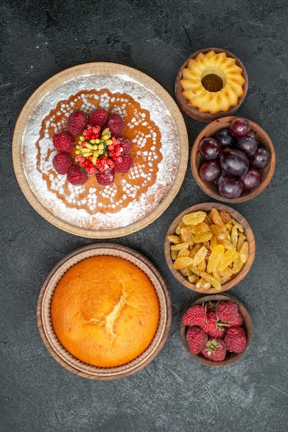 Vue de dessus délicieux gâteau aux framboises avec raisins secs et fruits sur la surface grise tarte au thé biscuit gâteau cookie sucré