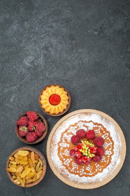 Vue de dessus délicieux gâteau aux framboises avec des raisins secs sur une surface grise tarte au thé biscuit gâteau biscuit sucré