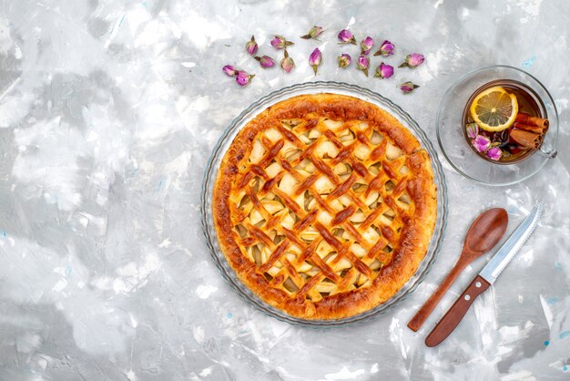 Une vue de dessus délicieux gâteau aux pommes avec thé chaud et fleurs gâteau biscuit sucre thé aux fruits