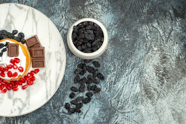 Vue de dessus délicieux gâteau crémeux aux grenades au chocolat et raisins secs sur fond clair-foncé