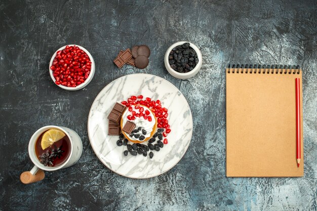 Vue de dessus délicieux gâteau crémeux avec des biscuits au chocolat et une tasse de thé sur le fond clair-foncé