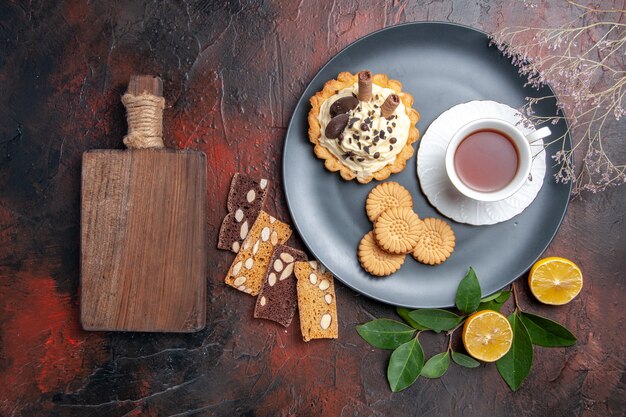 Vue de dessus délicieux gâteau crémeux avec du thé et des biscuits sur la table sombre dessert gâteau sucré