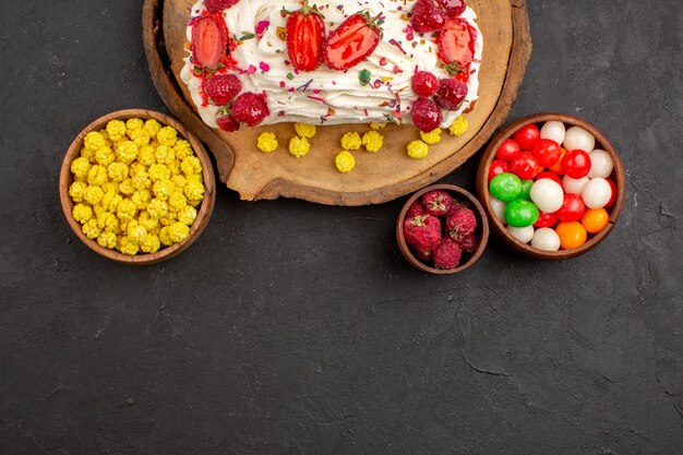 Vue De Dessus D'un Délicieux Gâteau Crémeux Avec Des Fruits Et Des Bonbons Sur Fond Noir