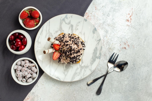 Vue de dessus délicieux gâteau crémeux avec des fruits frais sur une surface blanche biscuit au thé d'anniversaire gâteau à la crème sucrée