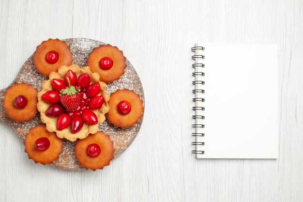 Vue de dessus délicieux gâteau crémeux avec des gâteaux et des fruits sur un bureau blanc