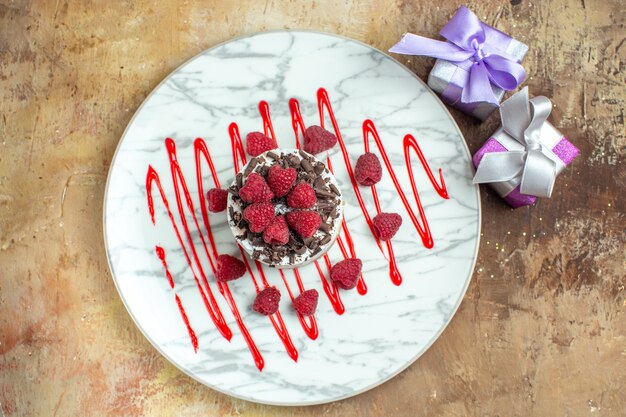 Vue de dessus délicieux gâteau crémeux à l'intérieur de la plaque avec des framboises sur fond marron