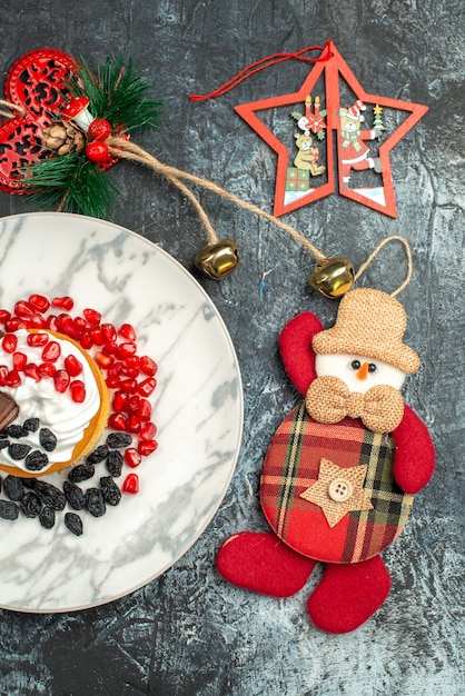Vue de dessus délicieux gâteau crémeux avec des raisins secs et des jouets de Noël sur fond clair-foncé
