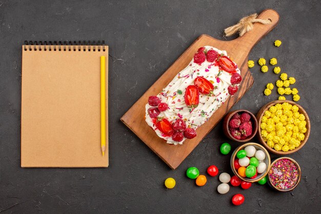 Vue de dessus d'un délicieux gâteau fruité avec des bonbons sur fond noir