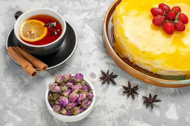 Vue de dessus délicieux gâteau fruité avec sirop jaune et tasse de thé sur la surface blanche gâteau biscuit biscuit au thé au sucre sucré