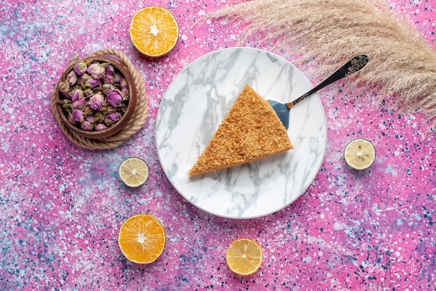 Vue de dessus délicieux gâteau rond tranche de celui-ci à l'intérieur de la plaque sur la tarte de bureau rose vif biscuit sweet bake