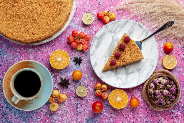 Vue de dessus délicieux gâteau rond tranche de celui-ci à l'intérieur de la plaque avec une tasse de thé sur le gâteau de bureau rose vif biscuit tarte aux fruits sweet bake