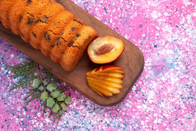 Photo gratuite vue de dessus délicieux gâteau sucré et délicieux avec des prunes sur le bureau rose.