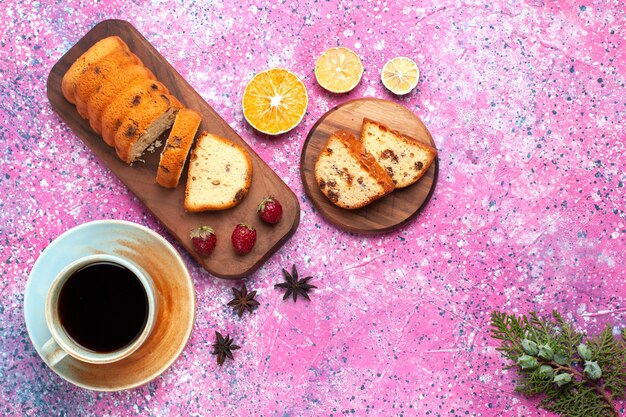 Vue de dessus délicieux gâteau sucré et délicieux tranché avec une tasse de thé sur le bureau rose.