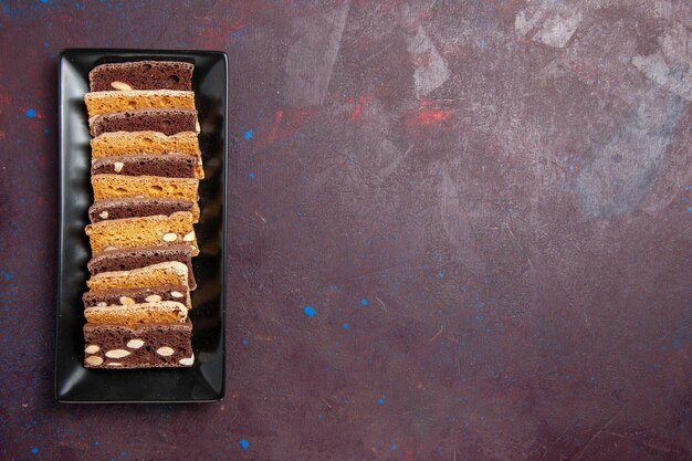 Vue de dessus délicieux gâteau en tranches avec des noix à l'intérieur du moule à gâteau sur fond sombre gâteau au cacao sucré tarte aux biscuits biscuit au sucre