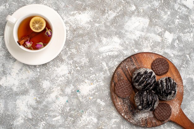 Vue de dessus de délicieux gâteaux au chocolat avec des biscuits et une tasse de thé sur une surface blanche