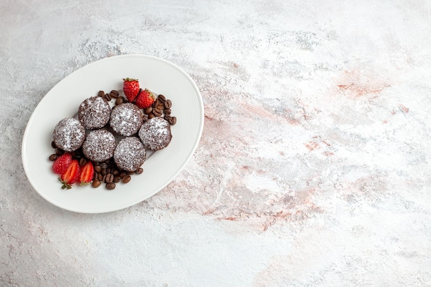 Vue de dessus de délicieux gâteaux au chocolat avec des fraises et des pépites de chocolat sur une surface blanc clair