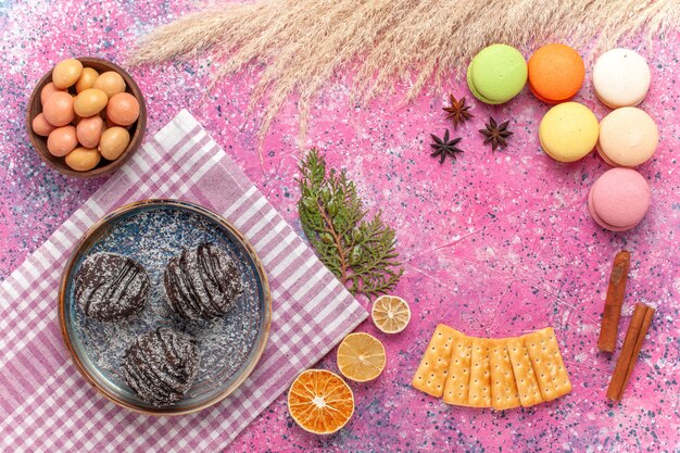 Vue de dessus de délicieux gâteaux au chocolat avec des macarons français sur le rose