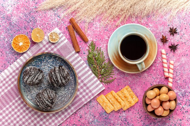 Vue de dessus de délicieux gâteaux au chocolat avec une tasse de thé sur le rose