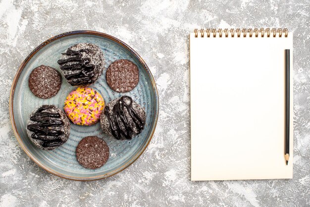 Vue de dessus de délicieux gâteaux aux boules de chocolat avec des biscuits sur une surface blanche