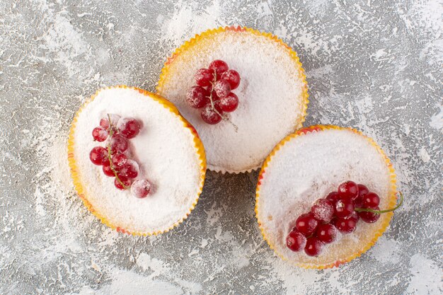 Vue de dessus de délicieux gâteaux aux canneberges avec des canneberges rouges sur le dessus des morceaux de sucre et de la poudre de bureau lumineux biscuit gâteau sweet