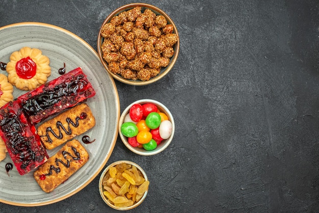 Vue de dessus de délicieux gâteaux aux fruits avec des biscuits et des bonbons dans l'obscurité