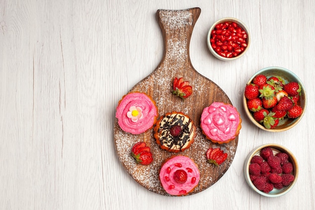 Vue de dessus de délicieux gâteaux aux fruits desserts crémeux avec des baies et des fruits sur fond blanc thé à la crème gâteau de dessert aux biscuits sucrés