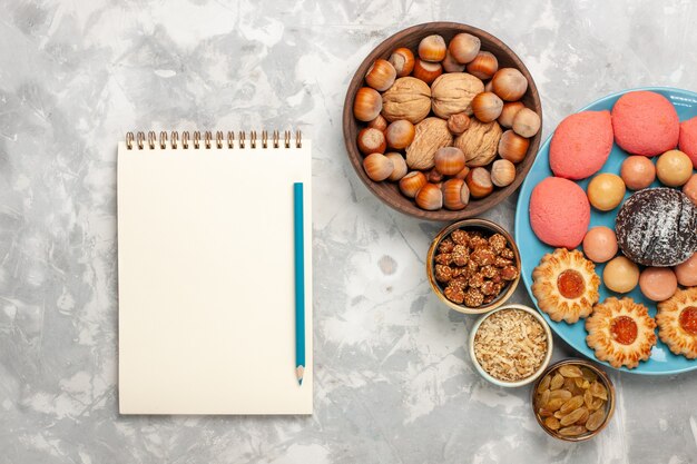 Vue de dessus de délicieux gâteaux aux noix de macarons et biscuits sur une surface blanche