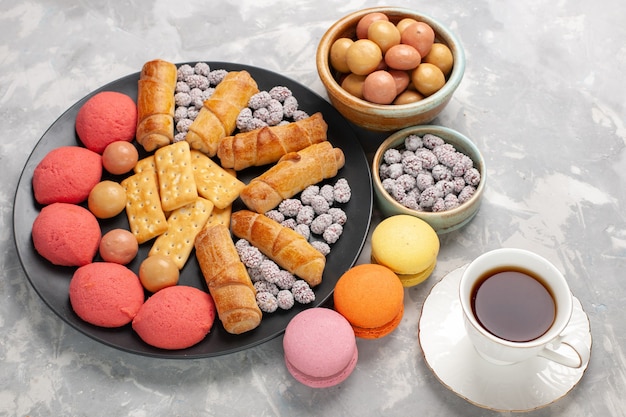 Vue de dessus de délicieux gâteaux avec des bagels, des bonbons, des biscuits et du thé sur le gâteau de bureau blanc clair biscuit biscuit tarte au sucre