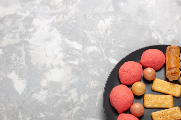 Vue de dessus de délicieux gâteaux avec des bagels et des bonbons sur un bureau blanc gris