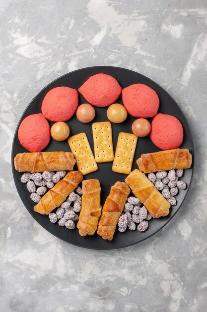 Vue de dessus de délicieux gâteaux avec des bagels et des bonbons sur un bureau blanc