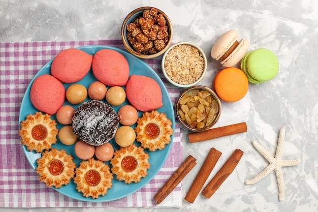 Vue de dessus de délicieux gâteaux avec biscuits raisins secs et macarons sur surface blanche