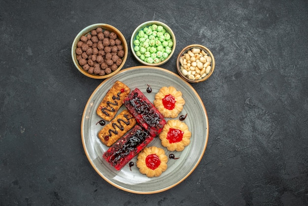 Vue de dessus de délicieux gâteaux bonbons fruités avec des biscuits et des noix sur fond sombre biscuit au sucre gâteau aux biscuits tarte sucrée